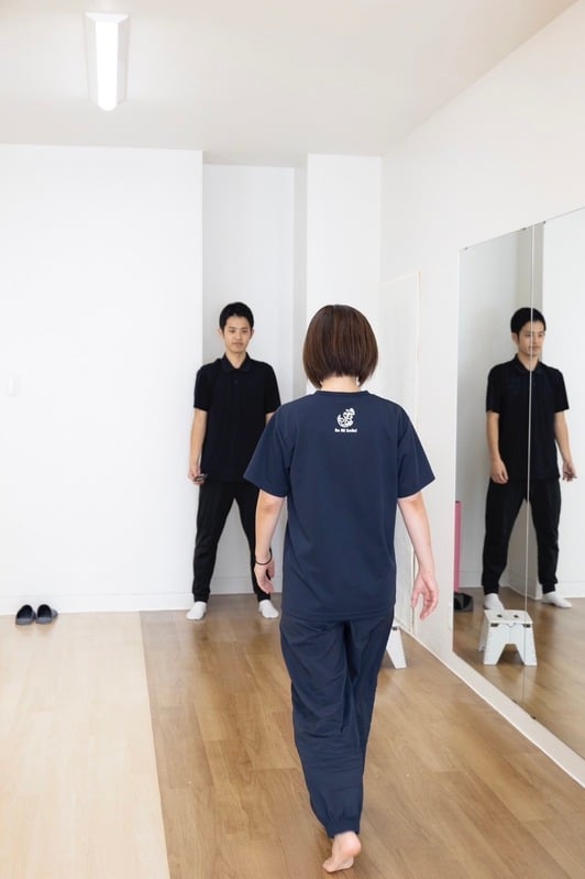 大きな鏡の前で歩き方を確認している様子